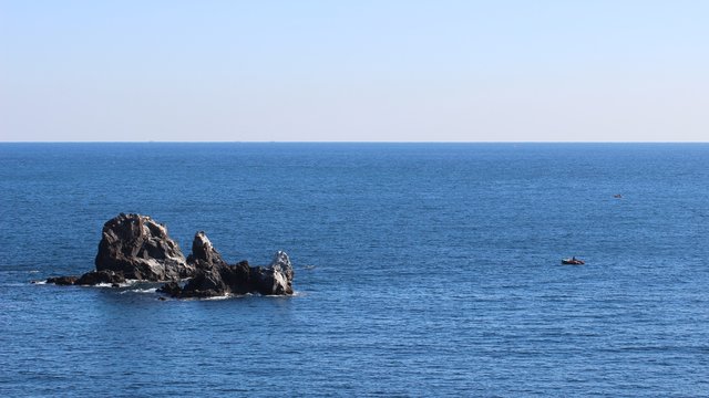 Ocean Rocks and Small Boats under Clear Sky